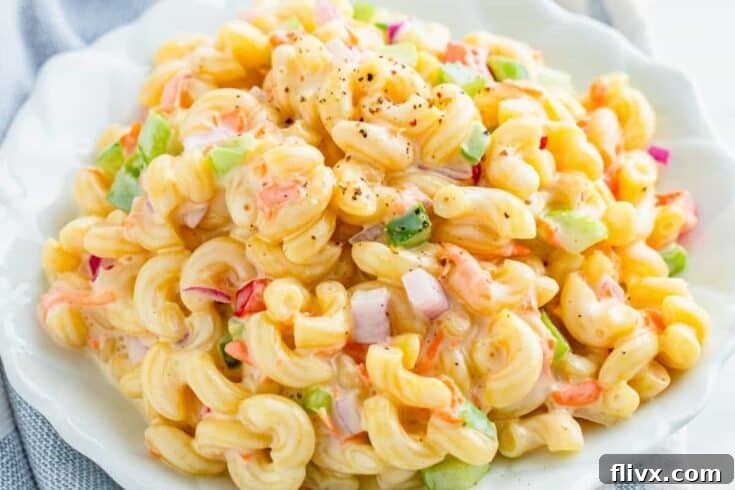 A large bowl of classic macaroni salad, garnished with fresh herbs.