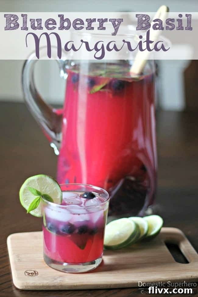 Refreshing blueberry basil margaritas in salt-rimmed glasses, garnished with blueberries and basil leaves.