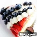 A festive red, white, and blue bundt cake topped with fresh berries and a creamy glaze.