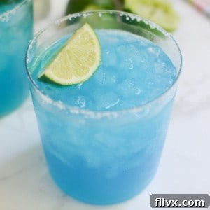Refreshing blue margaritas garnished with lime slices.