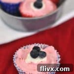 Mini red, white, and blue no-bake cheesecakes garnished with fresh berries.