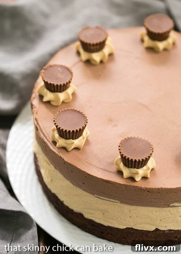 The finished Peanut Butter Chocolate Mousse Cake presented on a rustic basket weave serving plate, showcasing its beautiful, well-defined layers and the delicate decoration of mini Reese's cups on top.