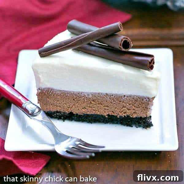 A perfectly sliced Triple Chocolate Mousse Pie on a square white plate, revealing distinct layers of chocolate crust, dark chocolate mousse, and white chocolate mousse. A red-handled fork rests beside it, inviting a taste.