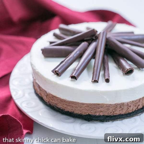 A stunning Triple Chocolate Mousse Pie presented on a pristine white serving plate, flanked by a folded red napkin. The distinct layers of dark and white chocolate mousse are clearly visible, topped with delicate chocolate shavings.