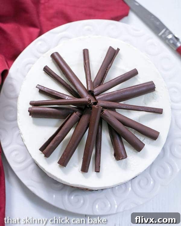 An overhead view of a beautifully garnished Triple Chocolate Mousse Pie on a white ceramic plate, featuring an abundance of chocolate curls scattered across its surface.