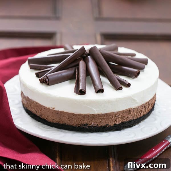 A whole Triple Chocolate Mousse Pie on a beautiful serving plate, generously topped with chocolate curls. The smooth surface of the white chocolate mousse and the rich dark chocolate mousse underneath promise a decadent experience.