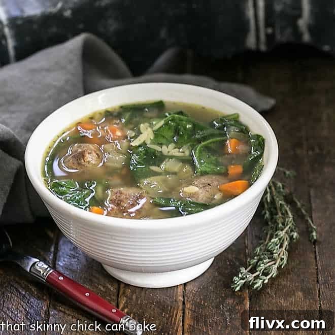 A delectable bowl of Italian wedding soup, garnished with a sprig of fresh thyme, ready to be enjoyed.