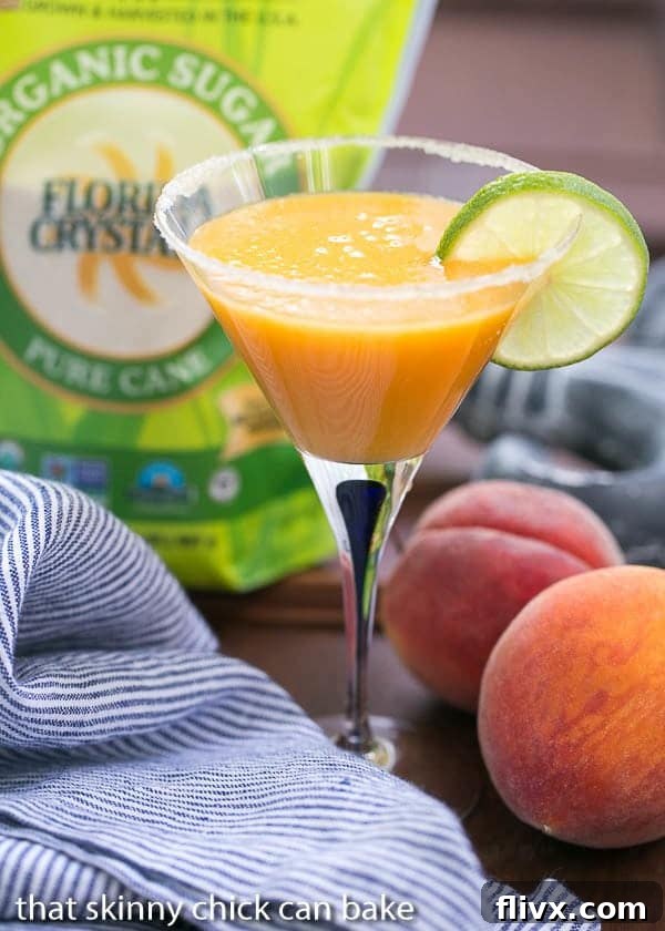 Peach Margaritas in a martini glass garnished with a slice of lime.