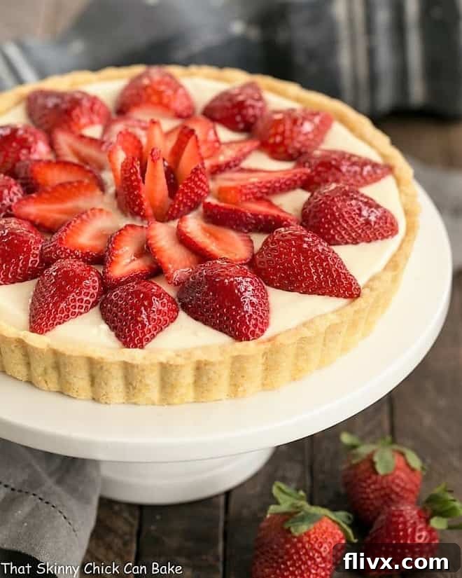 A stunning Strawberry Lemon Tart, elegantly presented on a cake stand, garnished with fresh strawberries and a delicate glaze.