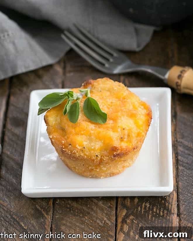 A single Cheesy Potato Cup on a square white plate, garnished with a fresh herb sprig.
