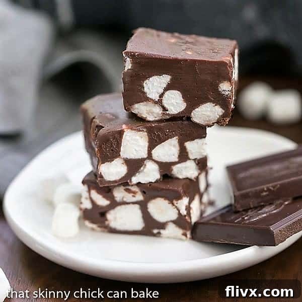 A stack of Chocolate Marshmallow Fudge squares on a small white plate, ready to be eaten.