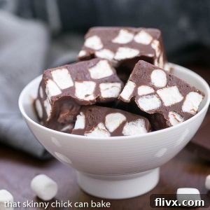 Chocolate marshmallow fudge squares in a white bowl, garnished with a few loose marshmallows.