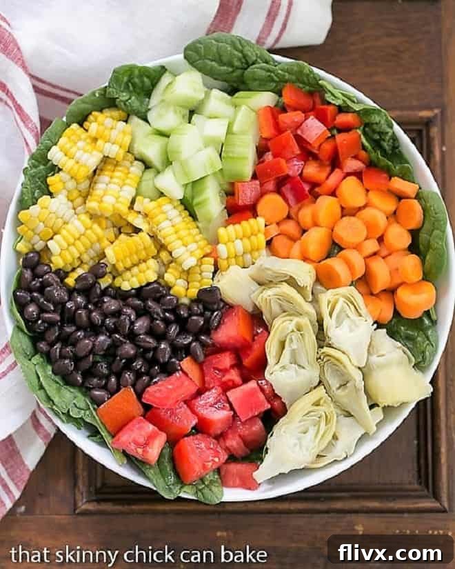 Overhead view of a beautifully composed Summer Vegetable Salad in a white bowl, showcasing layered ingredients.