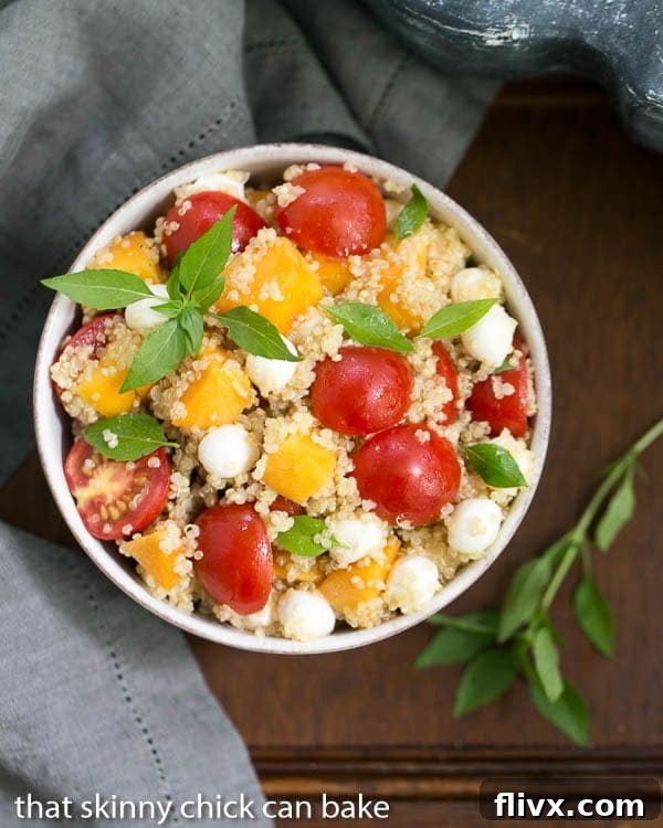Overhead view of a beautifully garnished Peach Quinoa Caprese Salad in a white bowl, ready to serve.