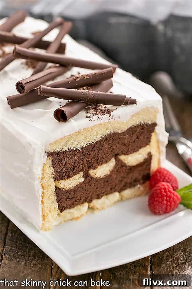 Layered No-Bake Chocolate Mousse Cake with a slice removed, adorned with elegant chocolate curls and a dusting of cocoa.