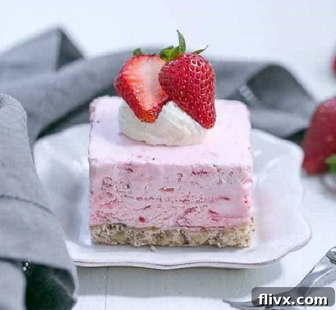 A tall slice of Mile High Strawberry Pie Dessert, showing layers of cream and fresh strawberries in a flaky crust.