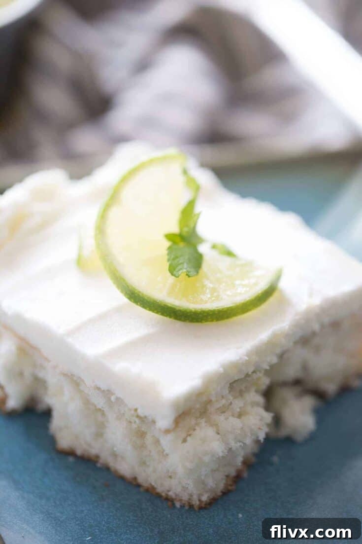 A slice of Mojito Poke Cake, showing the cake soaked with a rum-flavored filling and topped with minty frosting.