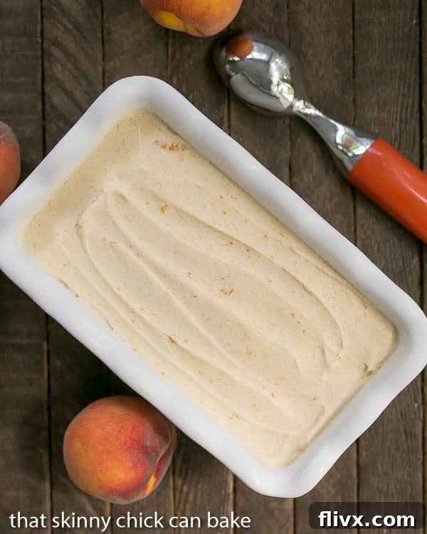 No Churn Roasted Peach Ice Cream presented in a white ceramic loaf pan, ready for freezing.