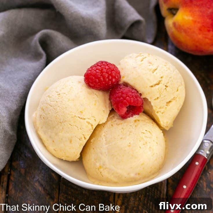 3 scoops of peach ice cream in a white ceramic bowl with 2 fresh raspberries
