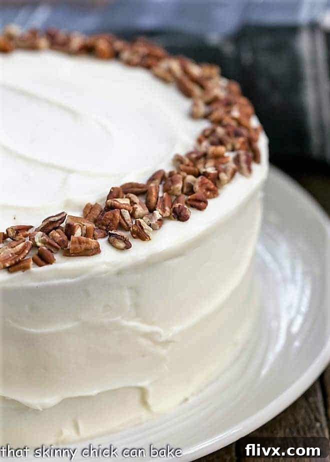 A mouth-watering view of a whole cheesecake stuffed carrot cake, expertly frosted with creamy cream cheese icing, ready to be served.