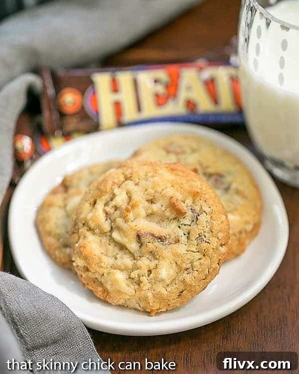 White Chocolate Toffee Chunk Cookies on a white ceramic plate with a glass of milk