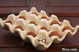Close-up of smooth, dark chocolate truffles coated in cocoa powder, arranged neatly in a ceramic egg crate