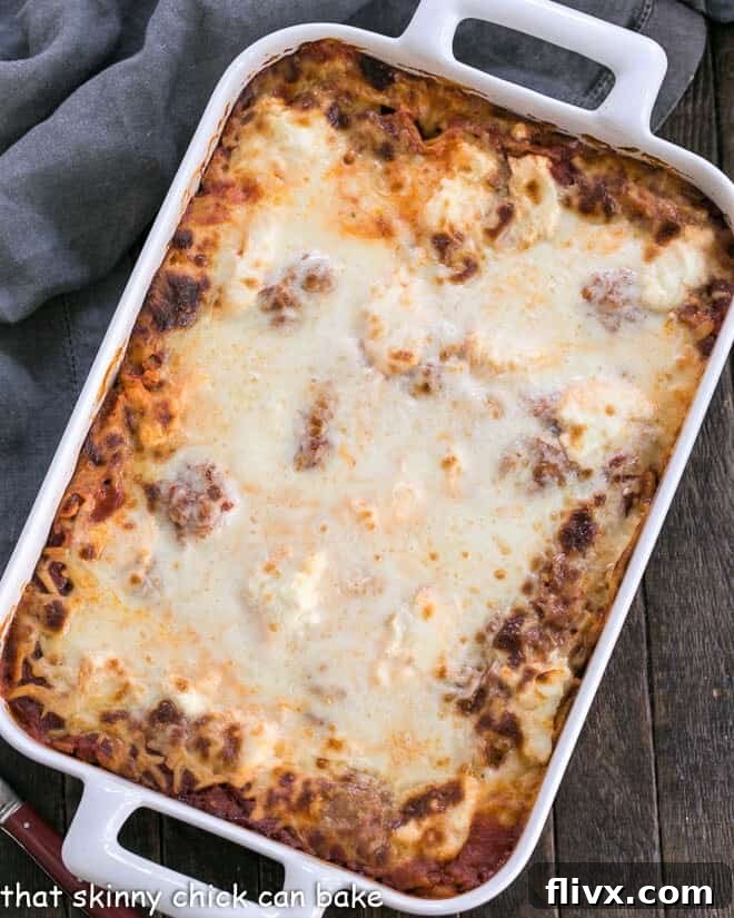 A large rectangular baking dish filled with golden-brown Ricotta Lasagna with Sausage, glistening with melted cheese and rich sauce, ready to be served.