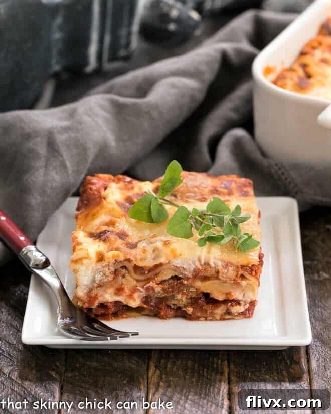A perfectly portioned slice of Sausage Ricotta Lasagna, showcasing distinct layers of pasta, meat sauce, ricotta, and melted mozzarella, presented on a white plate, garnished with a fresh sprig of oregano.