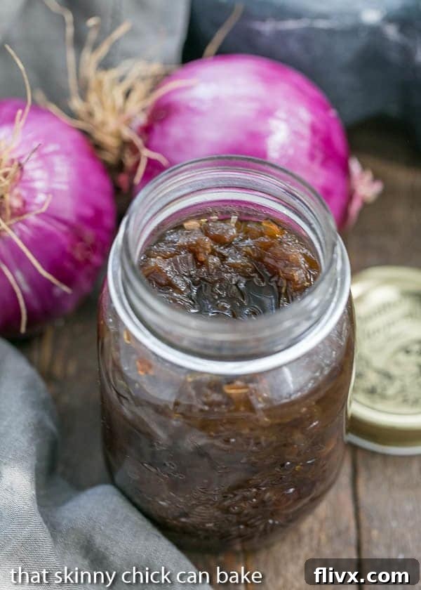 Homemade Red Onion Confit in a rustic glass canning jar, showcasing its deep, rich color and glossy texture.