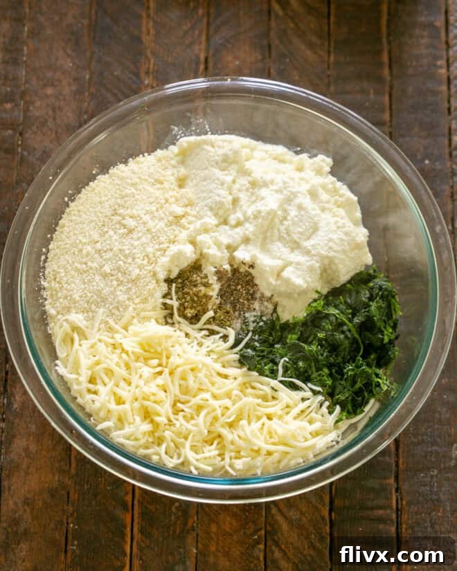 Ricotta cheese, mozzarella, Parmesan, eggs, oregano, salt, pepper, and squeezed dry spinach in a large mixing bowl.