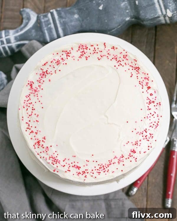 A full Red Velvet Checkerboard Cake, elegantly frosted with cream cheese frosting, resting on a white cake plate, ready to be sliced and admired.