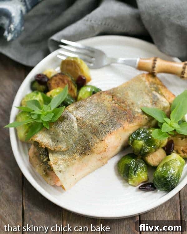 Potato Shingled Salmon on a white plate with brussels sprouts and lemon wedges, showcasing a beautifully cooked fillet