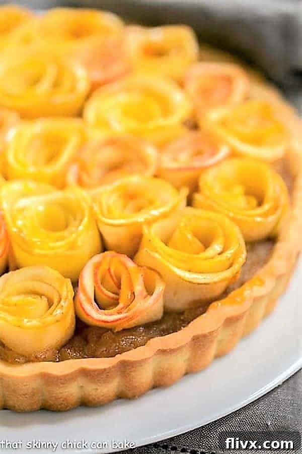Close up view of Rosette Apple Tart on a white cake plate, highlighting the intricate details of the apple roses.