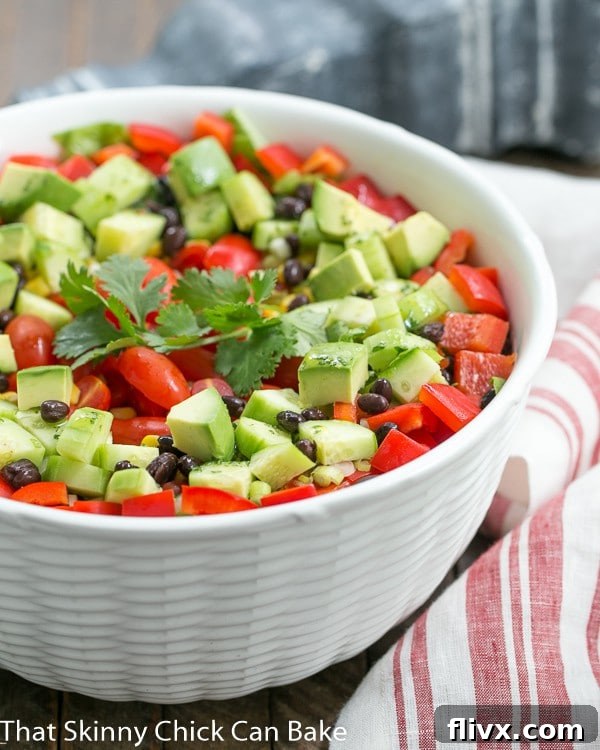 Fiesta Salad in a white ceramic bowl next to a white and red striped tea towel