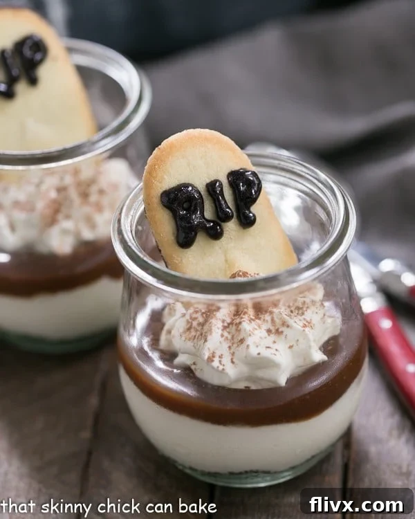 Close-up of Fudgy Tombstone Parfait layers: dark Oreo crust, creamy white cheesecake, and rich fudge sauce, ready for a tombstone cookie garnish.