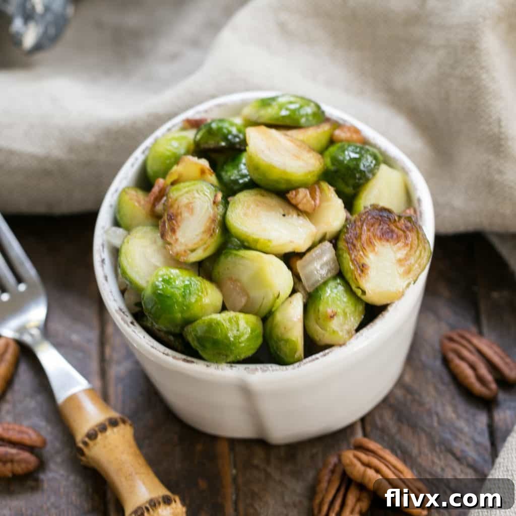 Overhead view of a small white bowl of sautéed Brussels sprouts with pecans