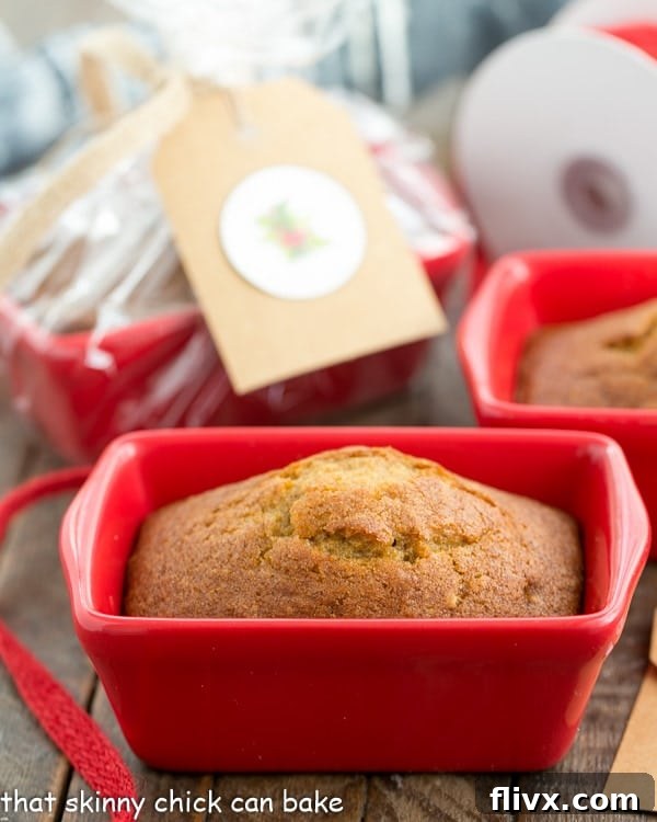 Freshly baked mini pumpkin breads cooling in a small red ceramic loaf pan, ready for packaging.