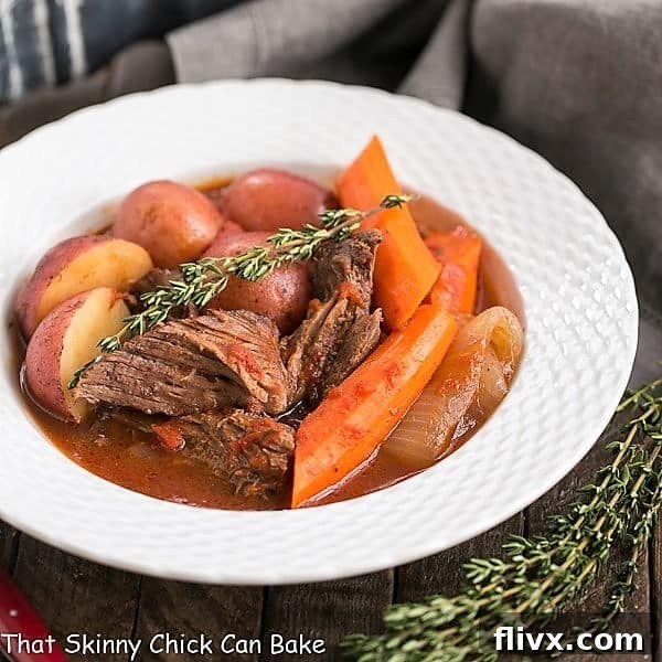 A close-up shot of a steaming easy pot roast in a white bowl, garnished with fresh thyme. Another sprig of thyme sits beside the bowl, highlighting the fresh ingredients.