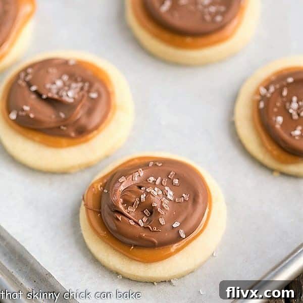 Freshly baked Chocolate Caramel Shortbread Cookies, artfully decorated and shimmering with a light sprinkle of sea salt, cooling on a parchment-lined sheet pan after baking.