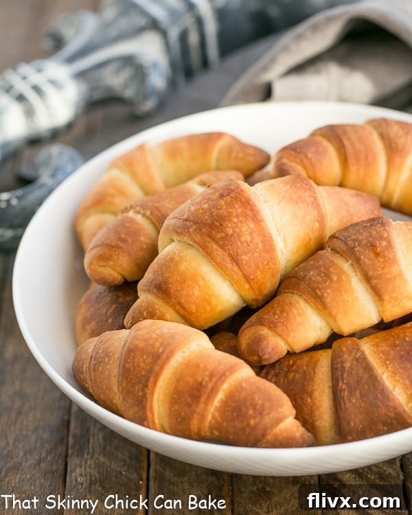 A cluster of golden-brown Buttery Homemade Crescent Rolls served in a white bowl, ready to be enjoyed.