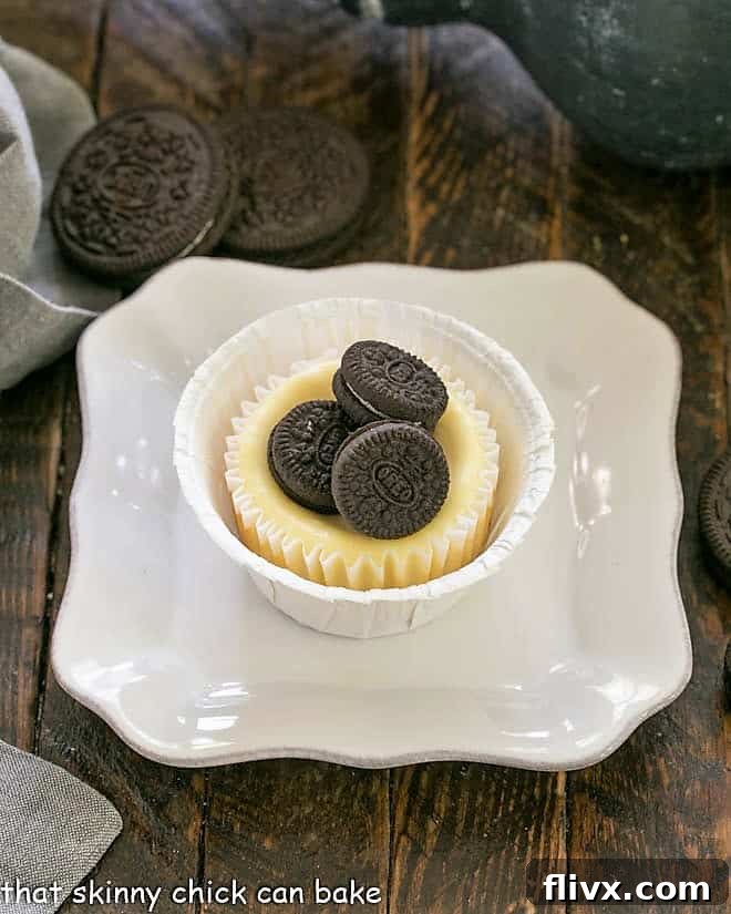 One Oreo cheesecake topped with 3 mini oreos on a square white plate.