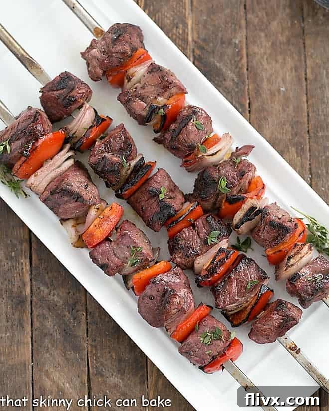 Marinated Greek Lamb Kebabs skewered on a white ceramic tray viewed from above.
