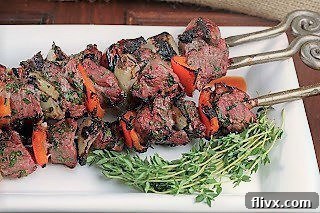 Greek kabobs on a white tray with thyme