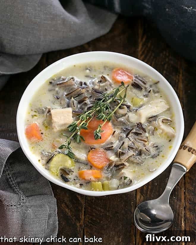 Homemade Chicken and Wild Rice Soup: Velvety Smooth and Comforting An overhead shot showcasing a rustic bowl of Chicken with Wild Rice Soup, accompanied by a bamboo-handled spoon, highlighting its inviting texture and rich ingredients.