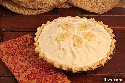 Top-down view of a beautifully prepared banana cream pie, showcasing its perfect round shape, creamy texture, and fresh banana garnishes