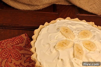 Detailed view of a freshly baked banana cream pie, highlighting the layers of crust, custard, and whipped cream, ready to be served