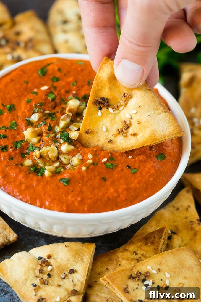 Muhammara (Roasted Red Pepper Dip) garnished with herbs.