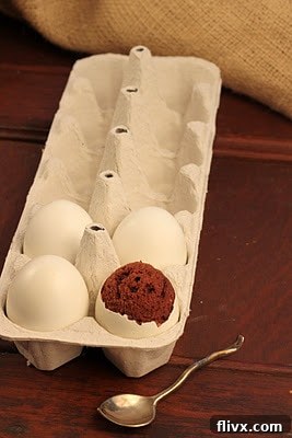4 eggs in a ceramic crate with one revealing brownie egg inside