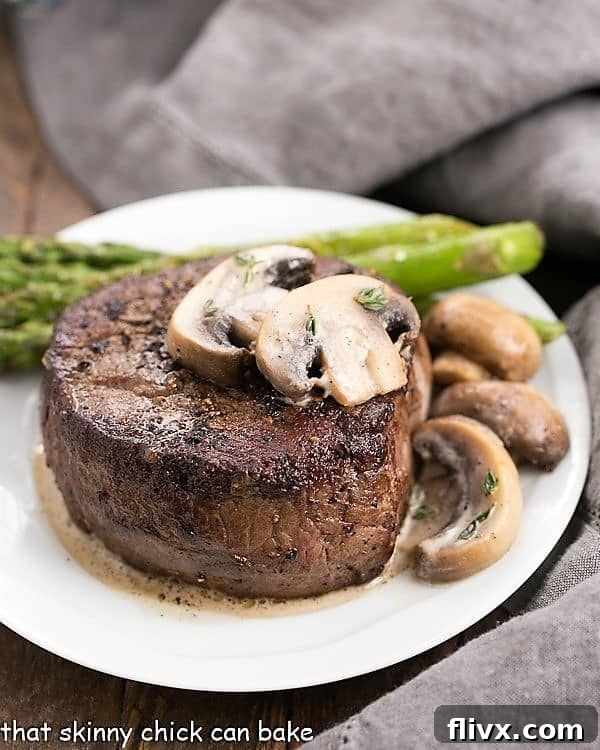 Mushroom Topped Pepper Steak topped with mushrooms on a white plate with asparagus spears, showcasing an elegant meal for two.