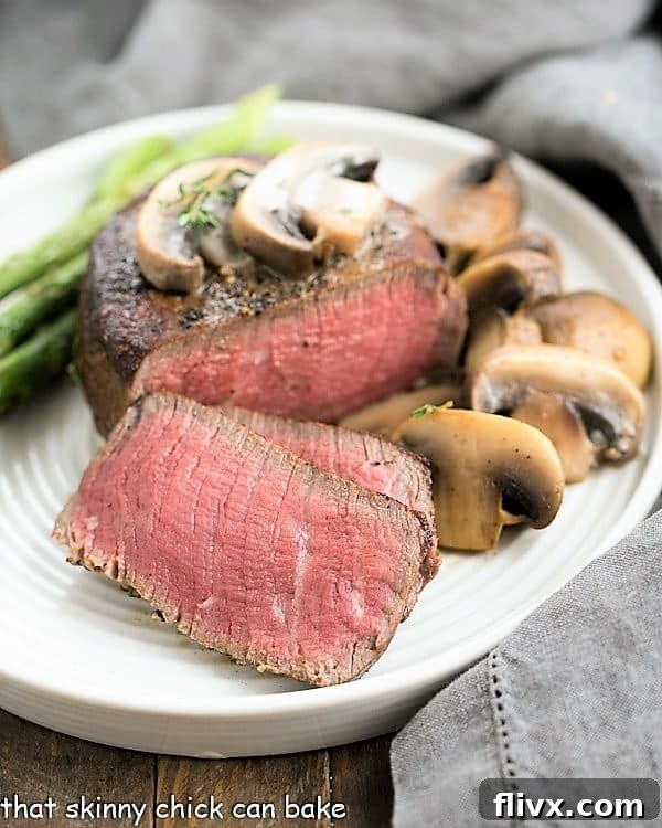 Mushroom Topped Pepper Steak sliced on a white dinner plate, garnished with fresh herbs and sauce.